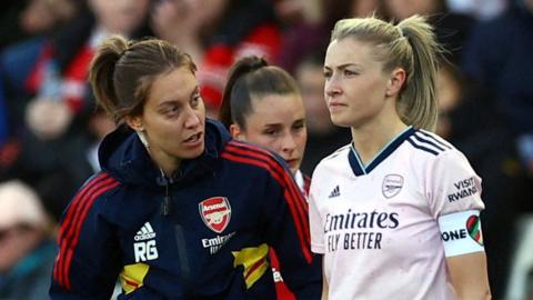 An Arsenal physio speaks to Leah Williamson after she has suffered an injury