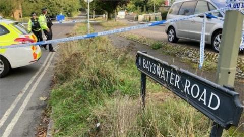 Police officers and a taped-off area next to a road sign for Bayswater Road