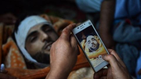 In this photograph taken on July 9, 2016, Kashmiri mourners take photographs of the body of Burhan Muzaffar Wani, the new-age poster boy for the rebel movement in the restive Himalayan state of Jammu and Kashmir, ahead of his funeral in Tral, his native town, 42kms south of Srinagar.