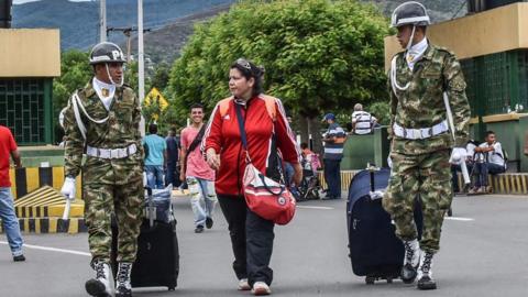 A woman is helped by Colombian soldiers crossing the Simon Bolivar international bridge from Venezuela