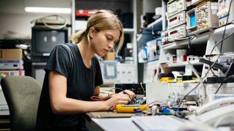 Woman working on an electrical circuit board