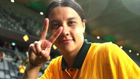 Sam Kerr makes a v-sign towards the camera