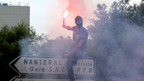 A masked protestor with a flare in Nanterre