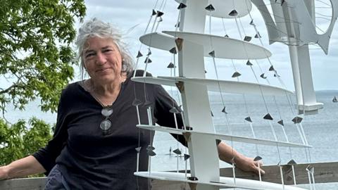 artist standing next to sculpture