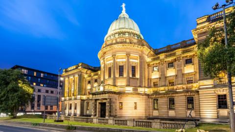 The brightly lit Mitchell library building as the sun sets 