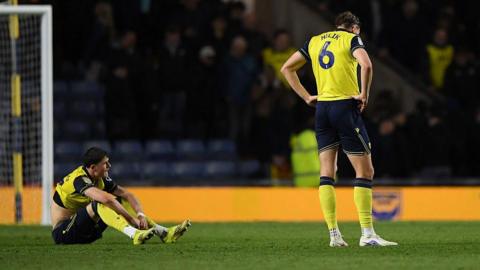 Oxford players Will Lankshear and Michal Helik look disconsolate following their defeat by Wrexham 