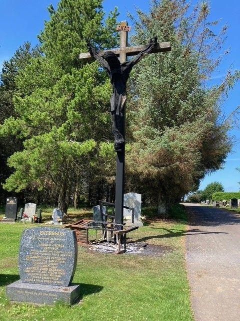 A large charred wooden crucifix, still upright in the cemetery