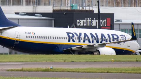 A Ryanair flight parked at Cardiff Airport, with the airport's logo seen in the background.