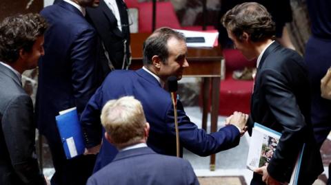 French Prime Minister Sebastien Lecornu shakes hands with French Education Minister Edouard Geffray after the results of the votes on two no-confidence motions