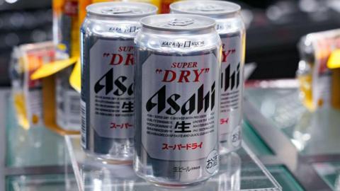 Three cans of Asahi beer in display with out of focus cans behind them