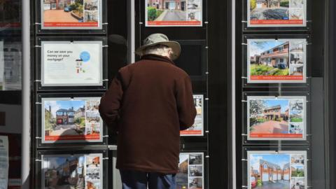 A man looks at houses for sale at an estate agents