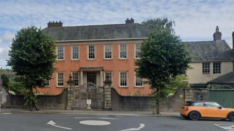 A Georgian house where William Wordsworth was born. The large two storey house is painted in a salmon colour and sits on Main Road in Cockermouth by a roundabout.