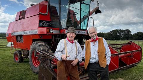 The Wurzels stood in front of a red combine harvester
