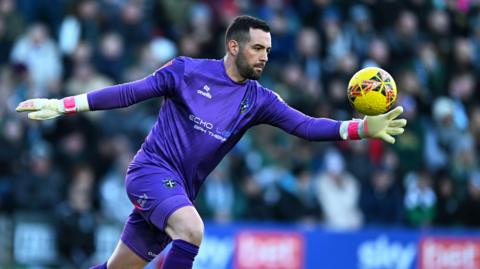 Dean Bouzanis kicking a ball out of hand