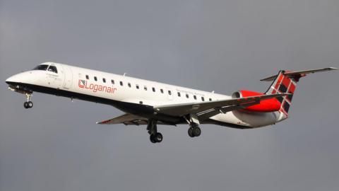 A Loganair passenger jet. The aircraft has a white fuselage, red jet engines and a tail decorated with a red, black and white tartan. The jet has its wheels down as it comes into land.