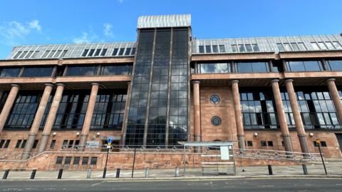 Newcastle Crown Court. It is an imposing building made of red brick and columns with large dark windows