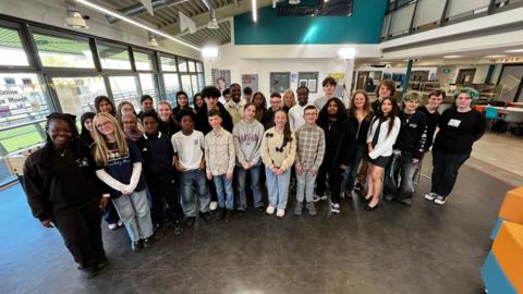 A young of young people posing for a photo in a television studio.