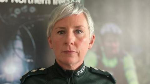 PSNI Ch Insp Yvonne McManus in PSNI uniform standing in front of a policing campaign board. She has short blonde hair. 