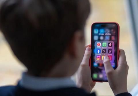 child looking at a mobile phone with icons of social media apps.