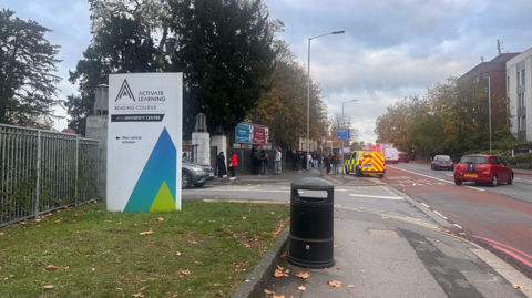 A police van parked outside Reading College on Kings Road as traffic flows out of it.