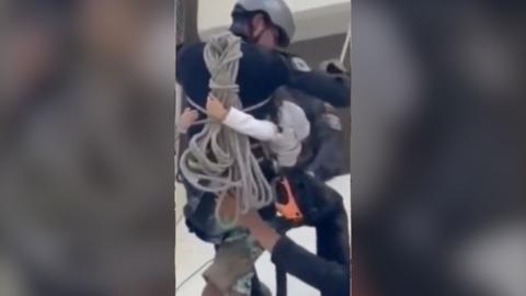 Man with a child wrapped around him exiting a building with a harness.