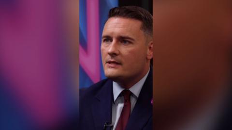 Wes Streeting wearing a navy blazer and red tie with a white shirt.