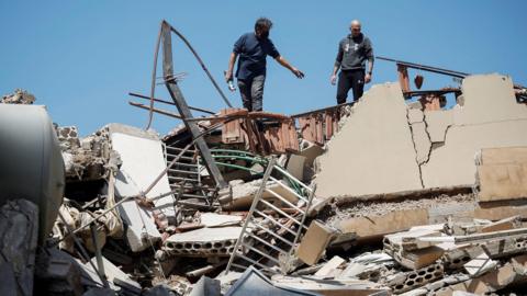 Two men stand on top of rubble in Tyre, Lebanon