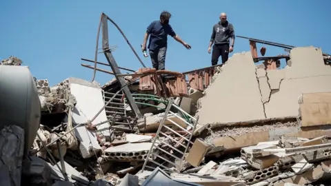 Two men stand on top of rubble in Tyre, Lebanon