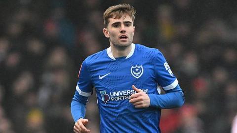 Zak Swanson in action for Porsmouth wearing a royal blue Pompey playing shirt
