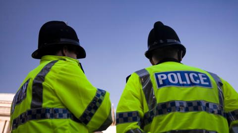 A generic image of the back of two police officers wearing high vis jackets. 