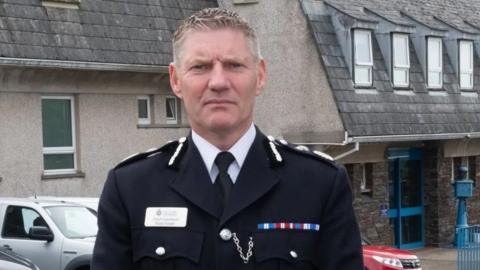 The Chief Constable looking serious in front of grey police headquarters