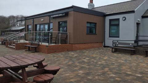 The exterior of a modern cafe with outside tables and benches