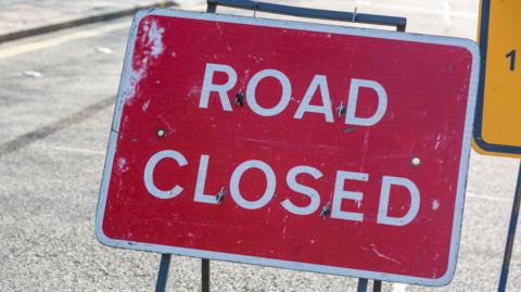 A red sign reading 'road closed' in capital letters stood on a road. 