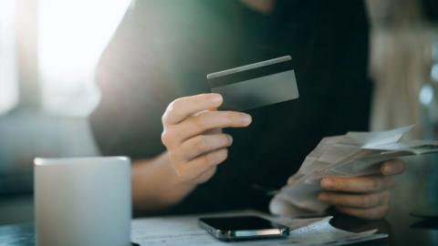 Cropped shot of young Asian woman holding credit card and expense receipts, handing personal banking and finance at home.