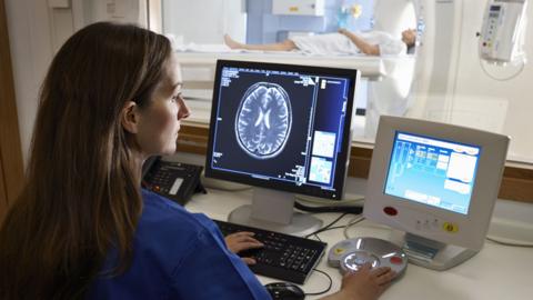 Radiologist looking at brain scan image on computer screen