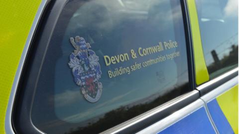 A picture of the side window of a police car. It has the Devon and Cornwall police logo on it.