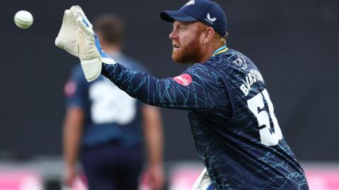 Jonny Bairstow in a blue Yorkshire shirt catches the ball wearing a wicket-keeping glove