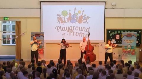 school children watching musicians in a school hall