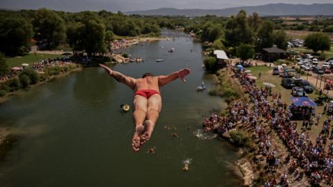 A diver jumps from a 22-metre-high bridge into the White Drin River during a traditional high diving competition near the town of Gjakova