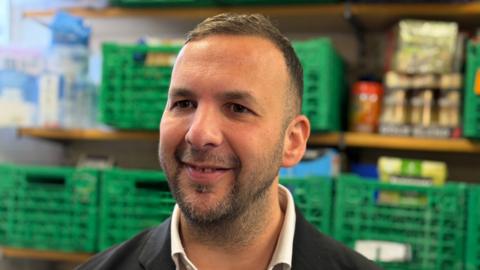 Green Party Leader Zack Polanski, a man in his early forties in a dark suit with dark hair, dark eyes and stubble 