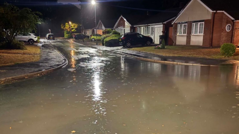 A flooded street at night, with water in the road