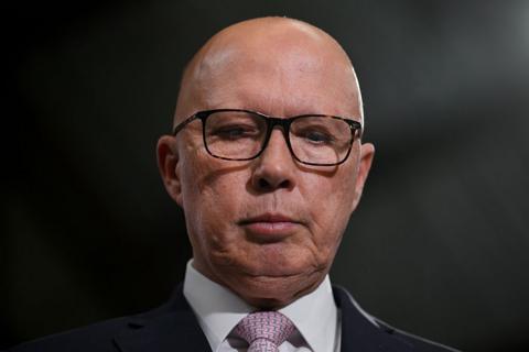 Peter Dutton, wearing glasses and a suit, looks down, his face neutral, in a close-up headshot