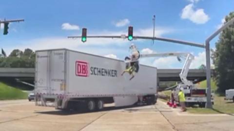Man dangling from harness at traffic junction, he is high in the air