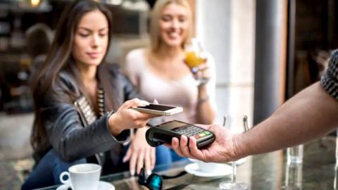 Woman paying with phone over card reader