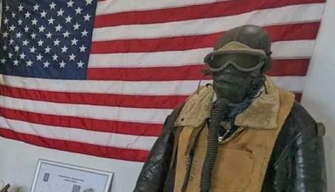 American flag on wall, with manikin in front dressed in WWII flying outfit