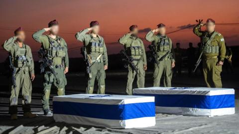 A photo released by the Israeli prime minister's office shows Israeli soldiers saluting the two coffins of Amiram Cooper and Sahar Baruch
