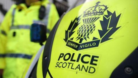 Police officers in yellow jackets and Police Scotland vehicle.