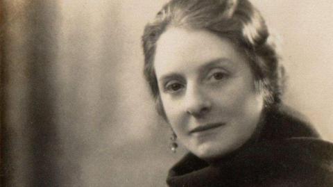 A sepia photograph of a woman with a scarf and earrings. 
