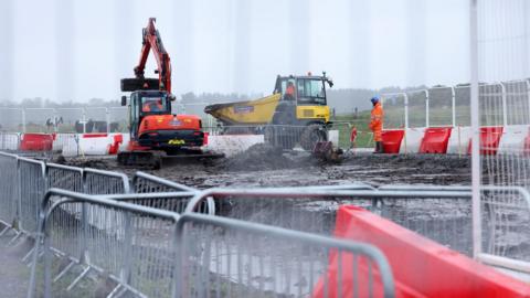 Diggers working in the mud at a train station