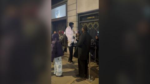 A man sits on the shoulders of another man to appear taller. 